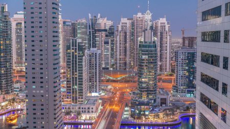 Téléchargez les photos : Vue aérienne sur Dubai Marina et JLT éclairé gratte-ciel et le yacht le plus luxueux du port de jour à la nuit transition timelapse. Tours le long de la zone de marche sur un front de mer. Dubai, Émirats arabes unis - en image libre de droit