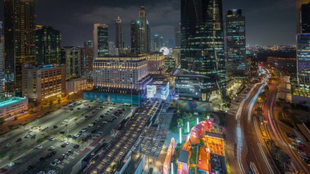 Foto de Panorama mostrando Dubai International Financial distrito noche timelapse. Vista aérea de las torres de oficinas de negocios. Rascacielos iluminados con hoteles y centros comerciales cerca del centro - Imagen libre de derechos