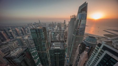 Photo for Skyline panoramic view of Dubai Marina showing canal surrounded by illuminated skyscrapers along shoreline aerial day to night transition timelapse. Floating yachts and boats during sunset. DUBAI, UAE - Royalty Free Image