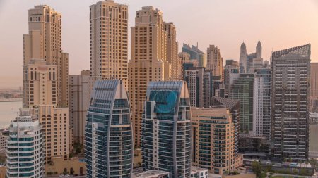 Foto de Dubai Marina rascacielos y JBR distrito con edificios de lujo y resorts timelapse aéreo durante el amanecer. Frente al mar con palmeras y césped verde - Imagen libre de derechos