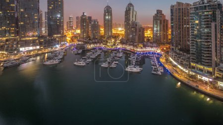 Foto de Bahía de yates de lujo en la ciudad noche aérea al día timelapse transición en Dubai Marina panorama antes del amanecer. Rascacielos modernos a lo largo del paseo marítimo y barcos flotando en el puerto - Imagen libre de derechos