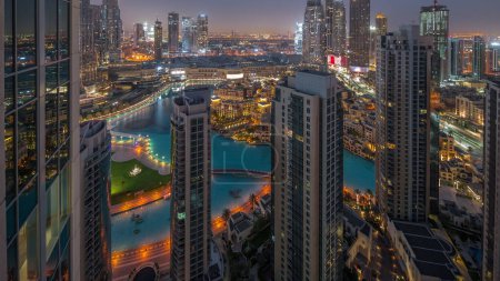 Foto de Dubai centro con fuentes y arquitectura futurista moderna noche aérea a día timelapse transición. Vista panorámica a rascacielos con casco antiguo y centro comercial - Imagen libre de derechos