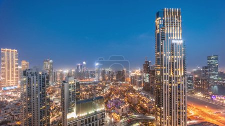 Téléchargez les photos : Vue panoramique aérienne d'une grande ville futuriste du jour à la nuit transition timelapse. Baie d'affaires et quartier du centre-ville avec de nombreux gratte-ciel et maisons traditionnelles, Dubaï, Émirats arabes unis skyline. - en image libre de droit