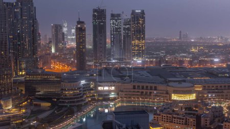 Téléchargez les photos : Dubaï centre-ville avec fontaines et architecture futuriste moderne nuit aérienne à la transition quotidienne timelapse. Vue sur les gratte-ciel avec quartier financier et centre commercial - en image libre de droit