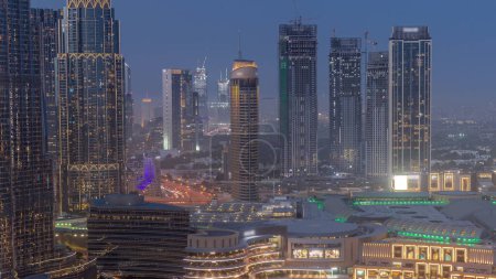 Téléchargez les photos : Dubaï centre-ville près des fontaines et de l'architecture futuriste moderne aérien jour à nuit transition timelapse. Vue sur les gratte-ciel du quartier financier et du centre commercial - en image libre de droit