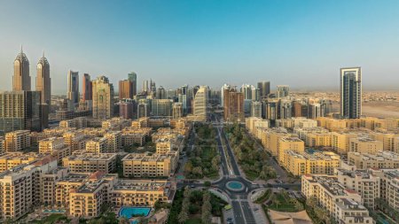 Foto de Panorama mostrando rascacielos en el distrito de Barsha Heights y edificios de poca altura en el timelapse aéreo del distrito de Greens. Dubai skyline con palmeras y árboles - Imagen libre de derechos