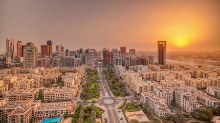 Téléchargez les photos : Lever de soleil sur les gratte-ciel dans le quartier de Barsha Heights et les bâtiments de faible hauteur dans le quartier des Verts timelapse panoramique aérienne. Skyline Dubaï avec ciel orange le matin - en image libre de droit
