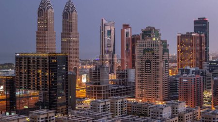 Téléchargez les photos : Des gratte-ciels dans le quartier de Barsha Heights et des tours internet de la ville aérienne nuit au jour passage timelapse. Skyline Dubaï avant le lever du soleil - en image libre de droit