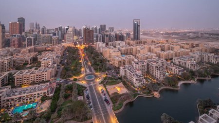 Téléchargez les photos : Des gratte-ciel dans le quartier de Barsha Heights et des immeubles de faible hauteur dans le quartier des Verts se succèdent de jour comme de nuit. Dubai skyline avec palmiers et zone de marche nead étang - en image libre de droit