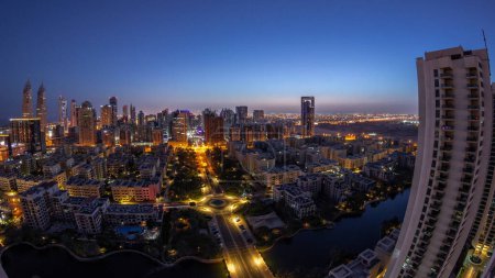 Photo for Skyscrapers in Barsha Heights district and low rise buildings in Greens district aerial night to day transition timelapse panorama. Dubai skyline with palms and trees - Royalty Free Image
