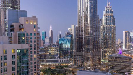 Foto de Vista aérea de los rascacielos del distrito del Centro Financiero Internacional de Dubai día a noche timelapse transición desde el centro. Torres de oficinas de cristal y hoteles con edificios modernos - Imagen libre de derechos