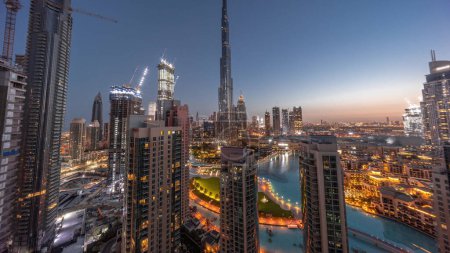 Photo for Dubai Downtown cityscape with tallest skyscrapers around aerial night to day transition panoramic timelapse. Construction site of new towers and busy roads with traffic from above - Royalty Free Image
