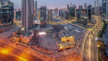 Photo for Business Bay Dubai illuminated skyscrapers with water canal aerial night to day transition panoramic timelapse. Mixed use development with residential and office towers sharing the footprint equally - Royalty Free Image