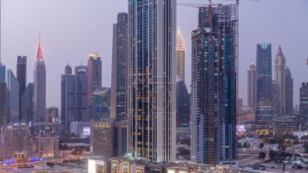 Foto de Fila de los altos edificios alrededor de Sheikh Zayed Road y DIFC distrito aéreo día a noche transición panorámica timelapse en Dubai, Emiratos Árabes Unidos. Rascacielos del Centro Financiero Internacional con superficie de vidrio - Imagen libre de derechos