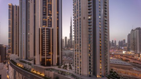 Téléchargez les photos : Les plus hauts gratte-ciel du centre-ville de Dubai situé sur la rue bouleward près du centre commercial aérien jour à la nuit transition timelapse. Zone de marche avec jardins sur le toit après le coucher du soleil - en image libre de droit