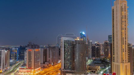 Photo for Skyscrapers at the Business Bay in Dubai aerial day to night transition panoramic timelapse. Road intersection and construction site of new towers with cranes after sunset, United Arab Emirates - Royalty Free Image