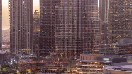 Foto de Centro comercial exterior con reastaurants día a noche timelapse transición después del atardecer en Dubai, Emiratos Árabes Unidos. Vista aérea superior con rascacielos más alto sobre un fondo - Imagen libre de derechos