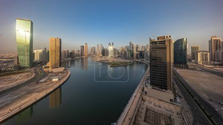 Téléchargez les photos : Paysage urbain panorama des gratte-ciel de Dubai Business Bay avec canal d'eau timelapse aérienne pendant toute la journée avec des ombres se déplaçant rapidement. Skyline moderne avec soleil réfléchi par les tours surface en verre - en image libre de droit
