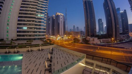 Photo for Aerial panorama of Dubai downtown and difc skyscrapers with busy traffic on intersection in Business bay district night to day transition timelapse. - Royalty Free Image