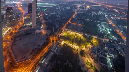 Téléchargez les photos : Villas dans le quartier de Zabeel avec des gratte-ciel sur un fond aérien nuit au jour transition timelapse avec lever du soleil à Dubaï, Émirats arabes unis. Circulation dans les rues avec maisons éclairées et routes - en image libre de droit