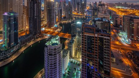 Foto de Vista de varios rascacielos en el bloque recidencial más alto de Dubai Marina aéreo de noche a día de transición timelapse panorámico con canal artificial. Muchas torres en el distrito JBR y yates antes del amanecer - Imagen libre de derechos