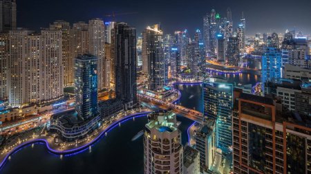 Panorama showing various skyscrapers in tallest recidential block in Dubai Marina and JDR district aerial night timelapse with artificial canal. Many towers and yachts