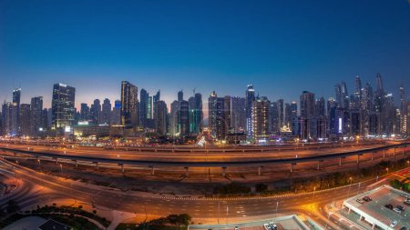 Téléchargez les photos : Panorama des gratte-ciel de Dubai Marina et de la route Cheikh Zayed avec métro ferroviaire aérien jour à nuit passage timelapse. Trafic sur une autoroute près des tours modernes après le coucher du soleil, Émirats arabes unis - en image libre de droit