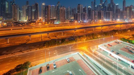 Foto de Dubai marina bloque más alto de rascacielos noche a día timelapse transición antes del amanecer. Vista aérea desde el distrito JLT a edificios de apartamentos, hoteles y torres de oficinas cerca de la autopista. - Imagen libre de derechos