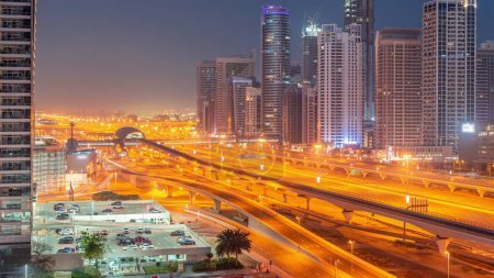 Foto de Dubai Marina rascacielos y Sheikh Zayed carretera con metro aéreo noche a día timelapse transición. Tráfico en una autopista cerca de torres modernas antes del amanecer, Emiratos Árabes Unidos - Imagen libre de derechos