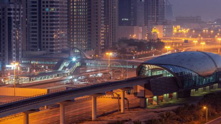 Téléchargez les photos : Bâtiment futuriste de la station de métro de Dubaï et des gratte-ciel de luxe derrière à Dubaï Marina, de nuit au jour, période de transition avant le lever du soleil. Circulation sur l'autoroute Sheikh Zayed, Émirats arabes unis - en image libre de droit
