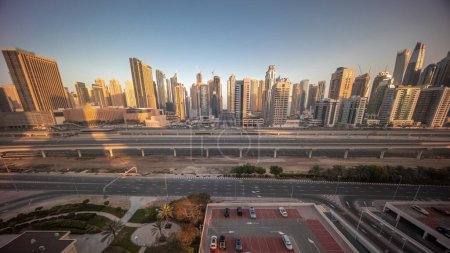 Téléchargez les photos : Dubai Marina gratte-ciel et Sheikh Zayed route avec métro ferroviaire aérien matin timelapse. Vue panoramique vers le bas sur la circulation sur une autoroute près des tours modernes au lever du soleil, Émirats arabes unis - en image libre de droit