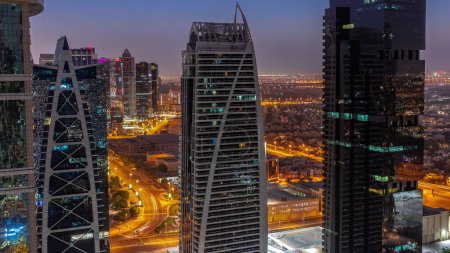 Téléchargez les photos : Bâtiments résidentiels hauts dans le quartier de JLT timelapse de transition aérienne de nuit au jour, qui fait partie du quartier mixte du centre multi-commodités de Dubaï. Villa maisons et circulation routière sur un fond - en image libre de droit