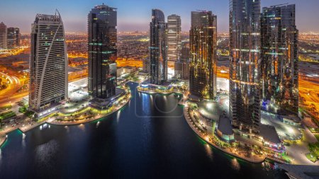 Foto de Edificios residenciales altos en el distrito JLT de noche aérea al día de transición panorámica timelapse, parte del distrito de uso mixto centro de productos básicos de Dubai. Rascacielos antes del amanecer - Imagen libre de derechos