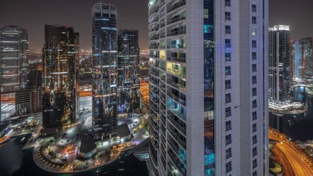 Foto de Panorama que muestra edificios residenciales altos en el timelapse aéreo nocturno del distrito JLT, parte del distrito de uso mixto del centro de productos múltiples de Dubai. Torres y rascacielos iluminados - Imagen libre de derechos