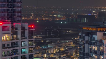 Téléchargez les photos : Luxury houses and villas near canal with towers aerial night  in Business Bay, Dubai, United Arab Emirates. Lake with road and lights of city skyline - en image libre de droit