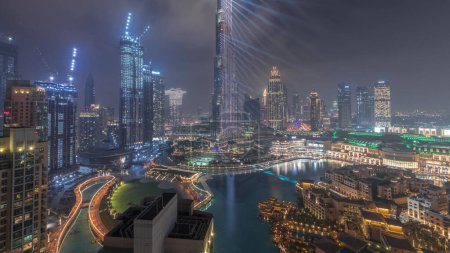 Foto de Skyscrapers rising above Dubai downtown during all night  with lights turning off, mall and fountain surrounded by modern buildings aerial top panoramic view with cloudy sky - Imagen libre de derechos