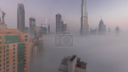 Foto de Aerial view of Dubai city early morning during fog night to day . Futuristic city skyline with skyscrapers and towers under construction from above - Imagen libre de derechos