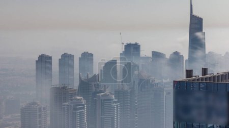 Foto de Fog covered skyscrapers in JLT district aerial . Top view from Dubai marina towers at evening time - Imagen libre de derechos