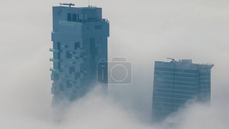Foto de Fog covered JLT skyscrapers and marina towers near Sheikh Zayed Road aerial  after sunrise. Residential building hazy morning - Imagen libre de derechos