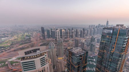 Photo for Panorama of Dubai Marina with JLT skyscrapers day to night transition , Dubai, United Arab Emirates. Aerial view from above towers after sunset with traffic on highway - Royalty Free Image