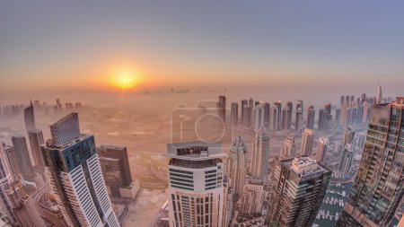 Photo for Panorama of Dubai Marina with JLT skyscrapers and golf course during sunrise , Dubai, United Arab Emirates. Aerial view from above towers foggy morning. City skyline with rooftops - Royalty Free Image