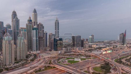 Téléchargez les photos : Panorama of Dubai Marina and media city highway intersection spaghetti junction day to night transition  after sunset. Illuminated tallest skyscrapers on a background. Aerial top view from JLT district. - en image libre de droit