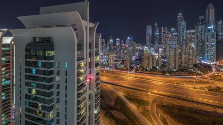 Téléchargez les photos : Panorama of Dubai Marina showing highway intersection spaghetti junction night . Illuminated tallest skyscrapers on a background. Aerial top view from JLT district. - en image libre de droit