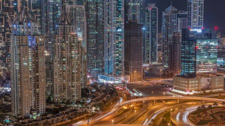 Photo for Aerial view on a big highway intersection night  in Dubai Marina with skyscrapers around, UAE. Cars traffic view from JLT district. Illuminated towers with light in windows - Royalty Free Image