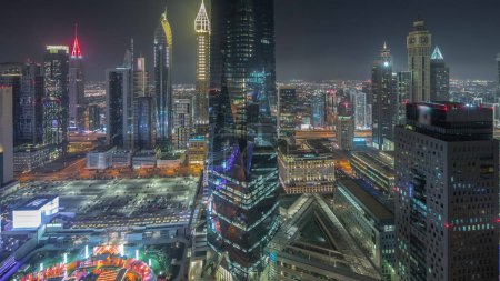 Téléchargez les photos : Panorama showing futuristic skyscrapers in financial district business center in Dubai on Sheikh Zayed road night . Aerial view from above with illuminated towers - en image libre de droit