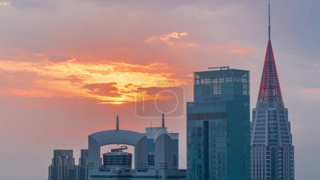 Téléchargez les photos : Sunset over financial center of Dubai city with luxury skyscrapers , Dubai, United Arab Emirates. Aerial view with orange sky and towers rooftops with spires - en image libre de droit