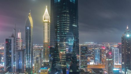 Foto de Financial center of Dubai city with illuminated luxury skyscrapers during all night , Dubai, United Arab Emirates. Aerial view with light in windows turning off and office towers - Imagen libre de derechos