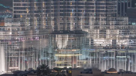 Téléchargez les photos : Dubai Fountain aerial night  located in an artificial lake in downtown. Entrance to the tallest skyscraper. Top view from above with evening illumination and old town houses - en image libre de droit