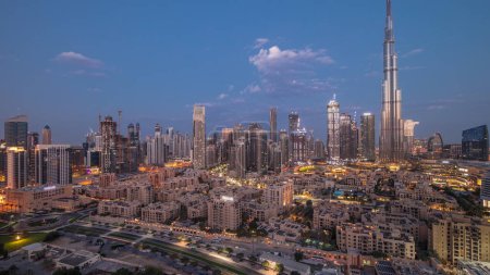 Photo for Dubai Downtown night to day transition  with reflections on tallest skyscraper and other towers view from the top during sunrise, United Arab Emirates. Traditional houses of old town and pink clouds - Royalty Free Image
