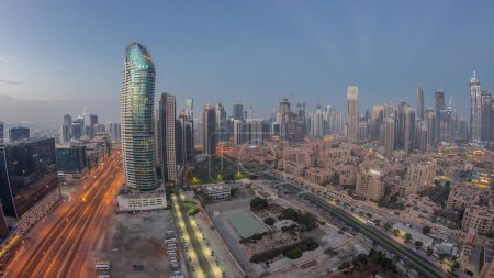 Foto de Panorama of Dubai's business bay towers aerial night to day transition . Rooftop view of some skyscrapers and new buildings under construction before sunrise - Imagen libre de derechos